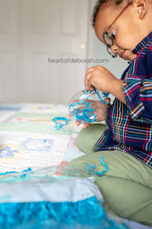 Fine motor skills at Christmas! Fill plastic ornaments with crinkle paper. Your toddler will love making their own ornament. 